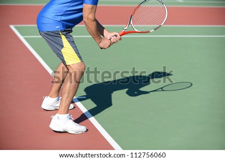 Tennis Player holding racket casting shadow on court