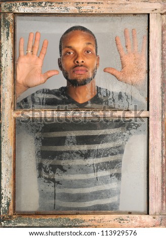 African American man looking out old grunge window