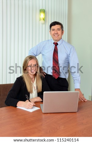 Young woman and mature man using computer in office setting