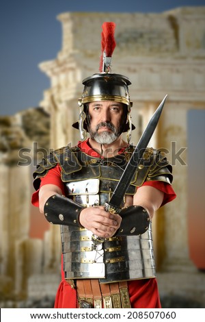 Portrait of Roman centurion holding sword with ancient buildings in background