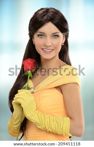 Portrait of young woman dressed in Victorian dress holding red rose