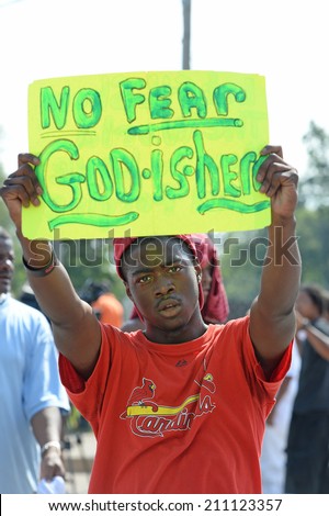 FERGUSON, MO/USA  AUGUST 15, 2014: Demonstrator holds sign at the site of destroyed Quick Trip after Police Chief Thomas Jackson release of the name of the officer that shot Michael Brown.