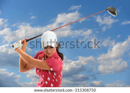Female golfer swinging golf driver during sunny day