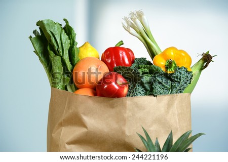 Assortment of fresh produce in grocery paper bag by window