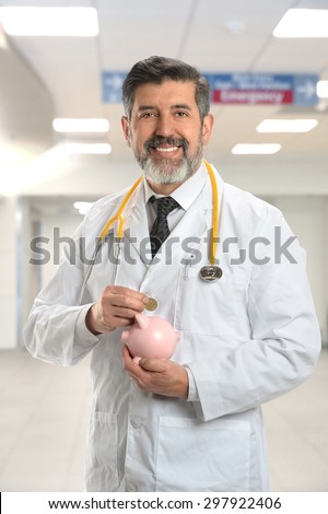 Portrait of Hispanic doctor putting money into piggy bank inside hospital