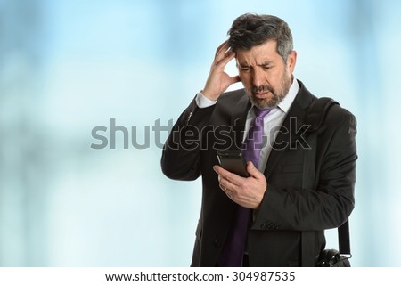 Worried Hispanic businessman looking at cellphone