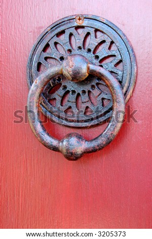 Vintage metal door handle on a red door.