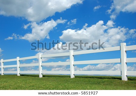 White fence against a bright sky with clouds