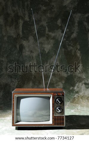 Vintage TV with knobs and antenna over a textured background