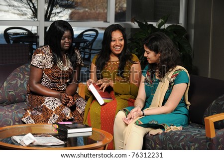 Group of female students dressed in traditional garments reading textbook