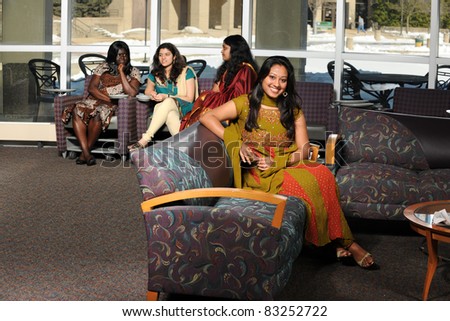 Indian student with diverse group of female students dressed in traditional clothing inside school setting