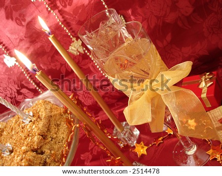 celebratory table (cake and candles, two glasses with champagne, gift boxes) on red