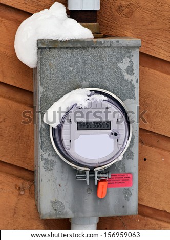 A Hydro Electric Smart Meter covered with snow displaying $ dollar signs on the readout.  Room for copy space or text.