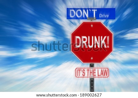 Traffic signs against a cloudy blue sky with the words Don\'t Drive Drunk, it\'??s the Law written on them.  Image is blurred to imply motion and blurred vision due to intoxication.