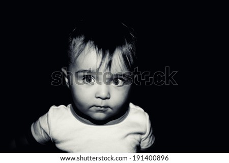 A portrait of a toddler in deep thought processed in lightly toned black and white.