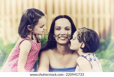 A close up family picture of a smiling mother together with her two happy daughters on either side of her.  Filtered for a retro, vintage look.
