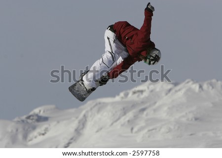 A snowboarder blasts a corked mute grab spin while jumping high off a freestyle ramp in the mountains,