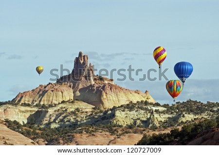A group of hot air balloons rise above the red sandstone of Red Rocks State Park near Gallup, New Mexico, and circle around the Church Rock formation