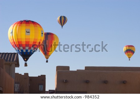 Hot air balloons pass very closely over the rooftops of houses in Albuquerque, New Mexico