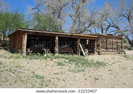 A stable building serving as the storage site for three wooden wagons.