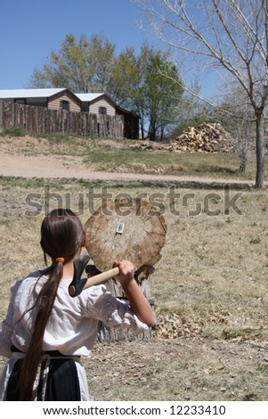 A young girl takes careful aim at a log target at which she\'s about to launch a throwing tomahawk