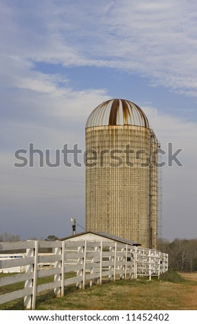 Vertical view of farm silo and wooden fence.