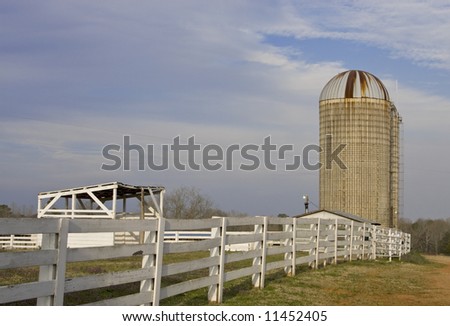 Horizontal view of farm silo and wooden fence.