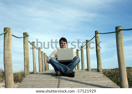 man portrait with computer on a beach landscape