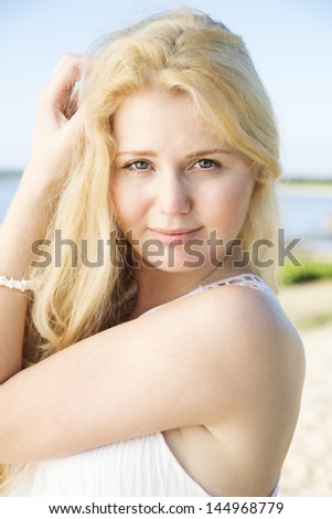 Zoomed portrait of woman in dress adjusts hairs