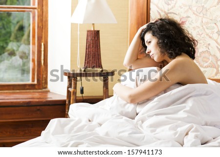 Woman under soft cover scratching her curly head
