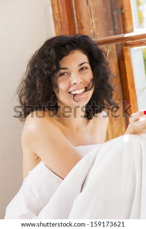 Smiling pretty woman under blanket bite hair perm