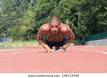 Muscular man doing exercise outdoors.
