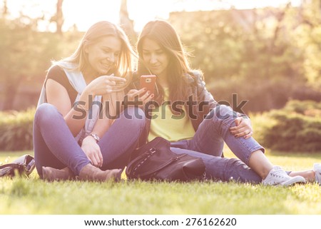 Female Friends Laughing and Looking at Cell Phone