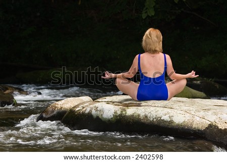 Woman meditating with yoga on a flat river rock, relaxing in one of many asanas.