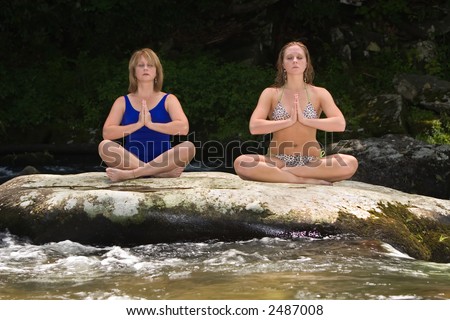 Mother and daughter meditating with Yoga on a flat rock in the Oconaluftee River, Great Smokey Mountains.