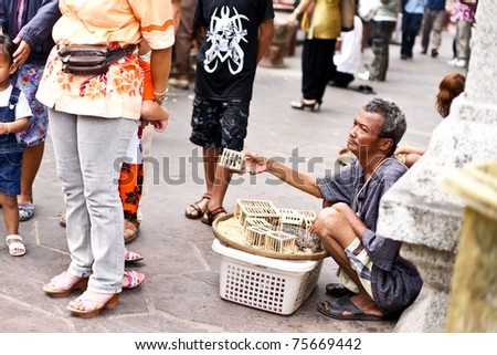LAMPHUN THAILAND - APRIL 12: An unidentified elderly man sells birds in cages to tourist to let free during Songkran Festival holidays on April 12, 2010 at Wat Phra That Hariphunchai Temple in Lamphun Thailand