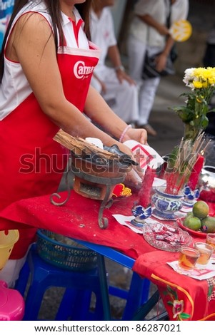 PHUKET, THAILAND - OCTOBER 2: An unidentified woman burns papers with with Chinese writing as part of ritual during the street parade of 2011 Vegetarian Festival on October 2, 2011 in Phuket, Thailand