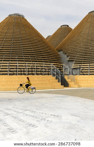 MILAN, ITALY - May 7: EXPO 2015, a cycling visitor  passes by wooden domes of Expo Centre building , shot  on may 7 2015  Milan, Italy