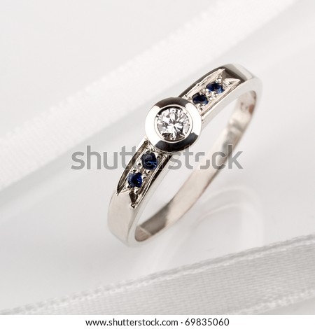 White gold ring whit diamond and sapphire on white satin.