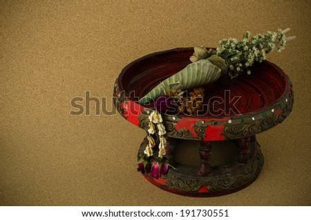 Dried flowers on red old tray with pedestal on cork background