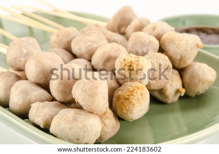 Meat ball with bamboo stick in green ceramic dish on white background