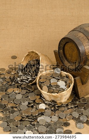Stack of coins with wooden barrel on brown sack background