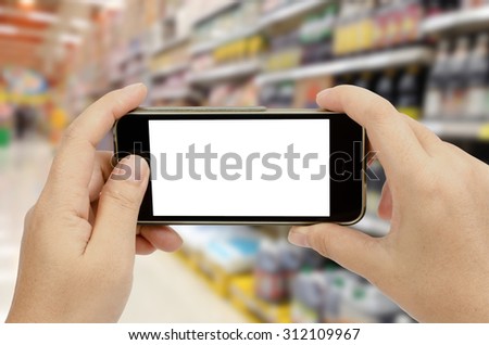 Smart phone in woman\'s hand on blur supermarket background with clipping path