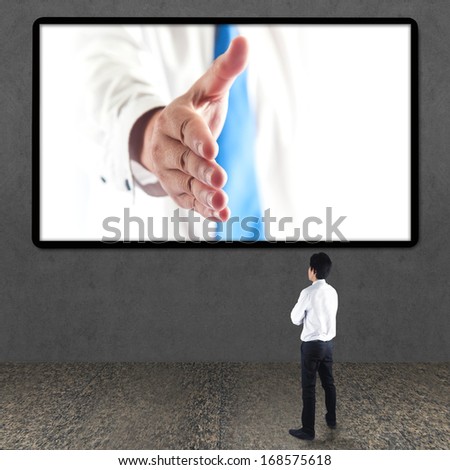 Business man gives a handshake out of TV screen