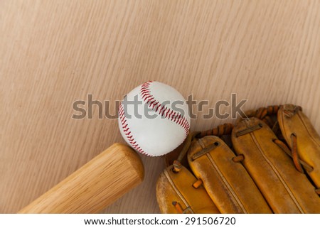 Baseball bat with ball and baseball glove on wood background