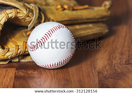 Baseball ball and baseball glove on wood background