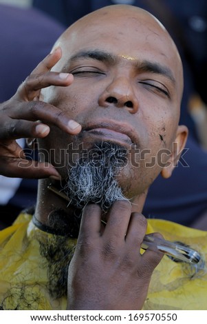 BATU CAVES, MALAYSIA - JANUARY 27: Devotees shave their heads and beards to symbolize purification and forgiveness of sins during Thaipusam on January 27 2013 in Batu Caves, Kuala Lumpur, Malaysia.