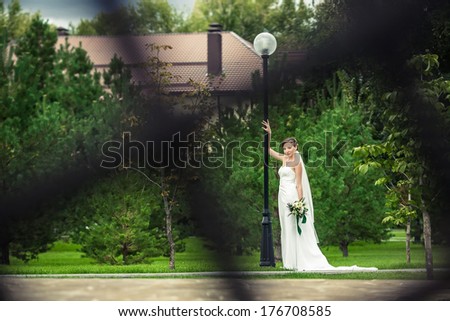 Bride in a flowing dress with a blurred background lawn.