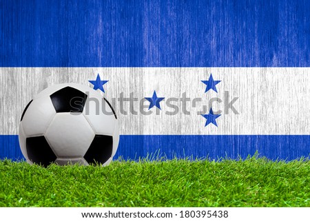 Soccer ball on grass with Honduras flag background close up