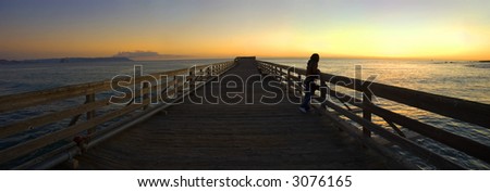 a woman watching the sunset from a pier